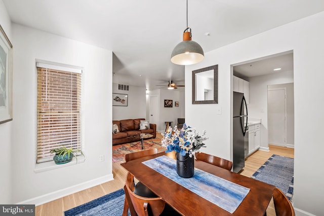 dining space with a ceiling fan, baseboards, visible vents, and light wood-type flooring