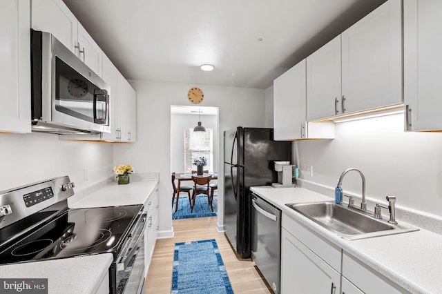 kitchen featuring a sink, light countertops, white cabinets, appliances with stainless steel finishes, and light wood-type flooring