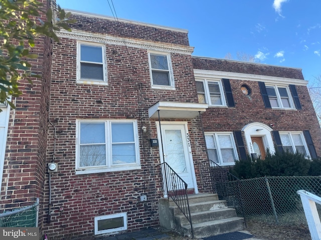 townhome / multi-family property featuring fence and brick siding