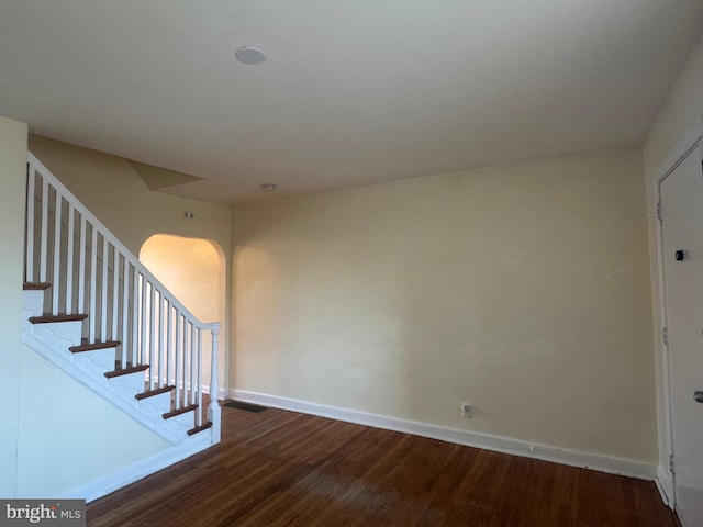 stairs featuring visible vents, wood finished floors, baseboards, and arched walkways