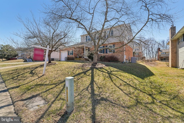 view of front facade with brick siding, an attached garage, and a front lawn