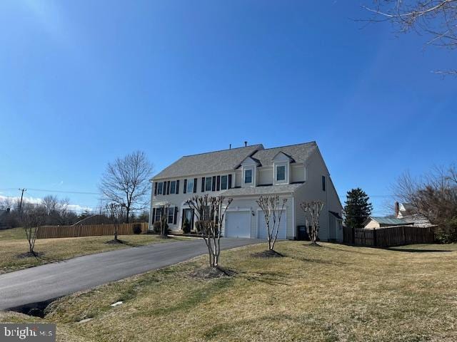 view of front facade featuring an attached garage, aphalt driveway, a front yard, and fence