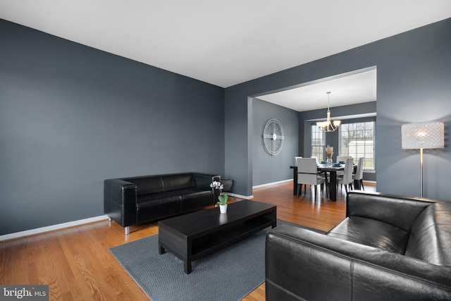 living room with light wood-type flooring, a notable chandelier, and baseboards