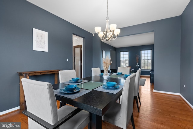 dining room with wood finished floors, an inviting chandelier, and baseboards