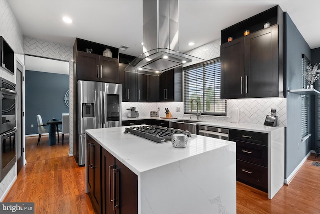 kitchen featuring stainless steel appliances, recessed lighting, island exhaust hood, and backsplash