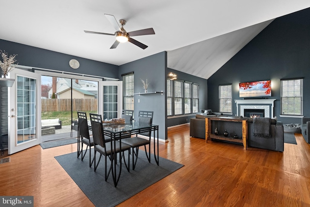 dining area featuring wood finished floors, ceiling fan, a glass covered fireplace, and plenty of natural light