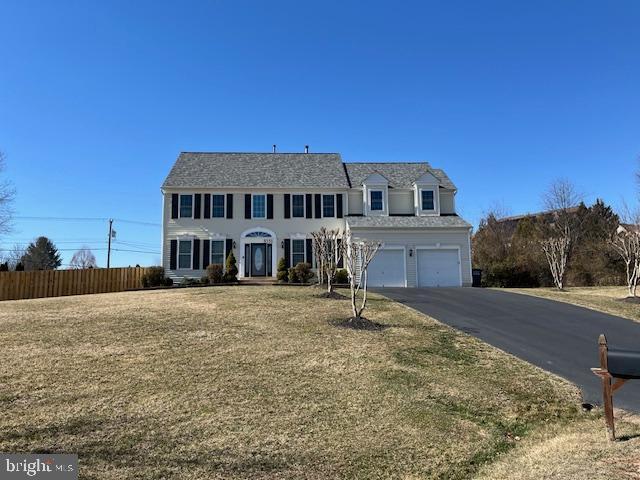 view of front facade with an attached garage, fence, and aphalt driveway