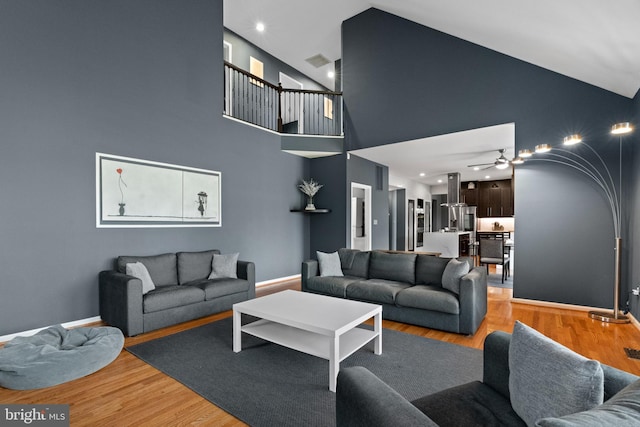 living room with visible vents, ceiling fan, high vaulted ceiling, and light wood finished floors