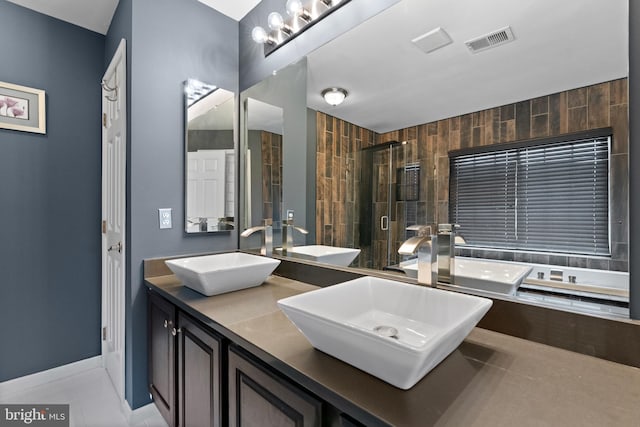 bathroom with visible vents, a sink, and a stall shower