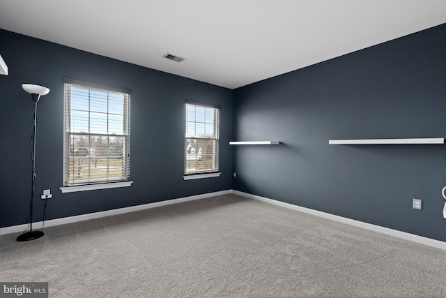 spare room with carpet flooring, visible vents, and baseboards