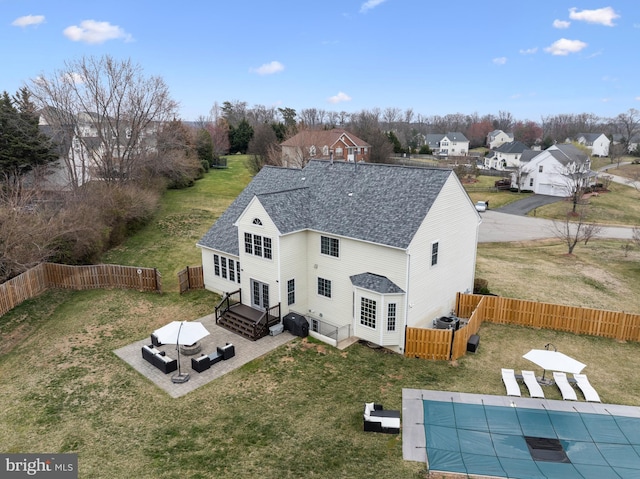 back of property with a shingled roof, a lawn, a fenced backyard, a patio, and a fenced in pool