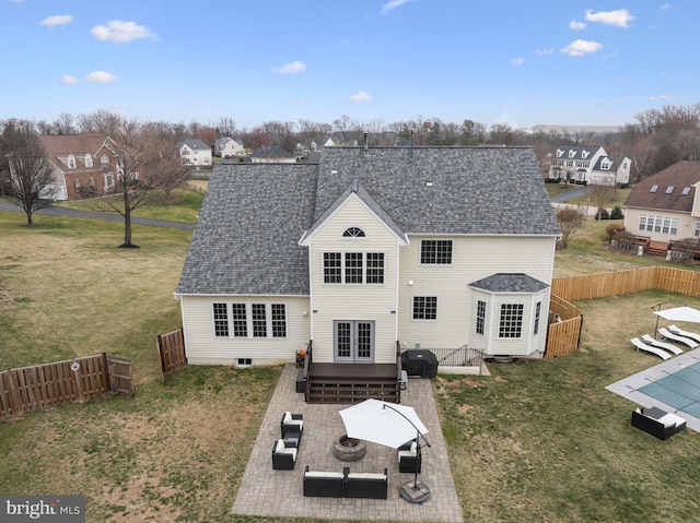 back of property featuring a yard, a fenced backyard, a shingled roof, and a residential view