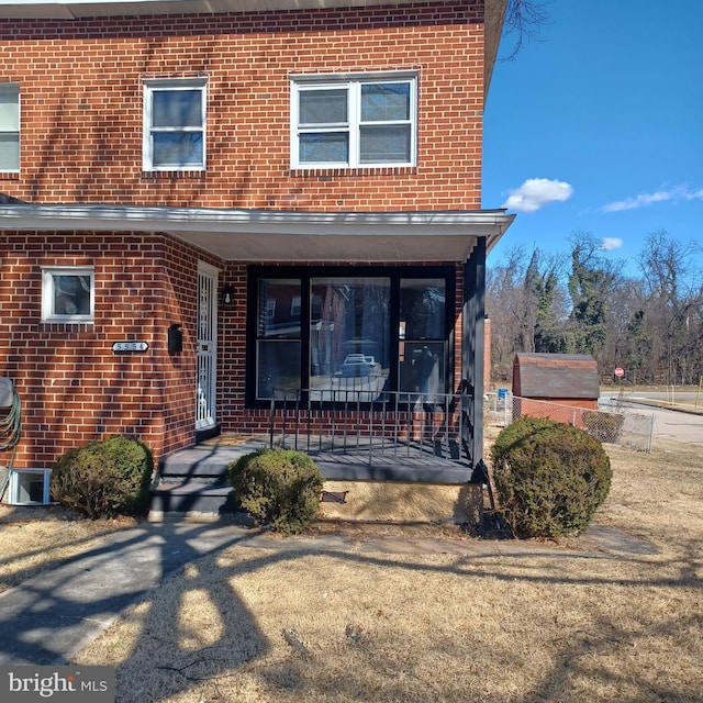 property entrance with covered porch and brick siding