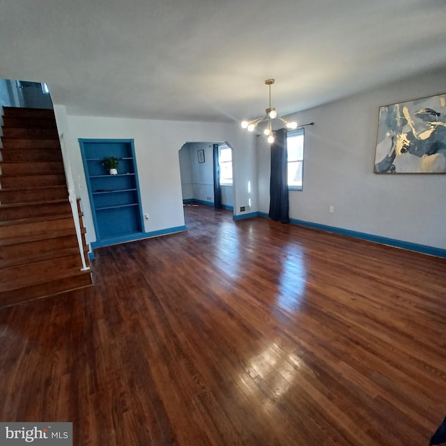 unfurnished living room featuring built in features, dark wood-style flooring, stairway, and baseboards