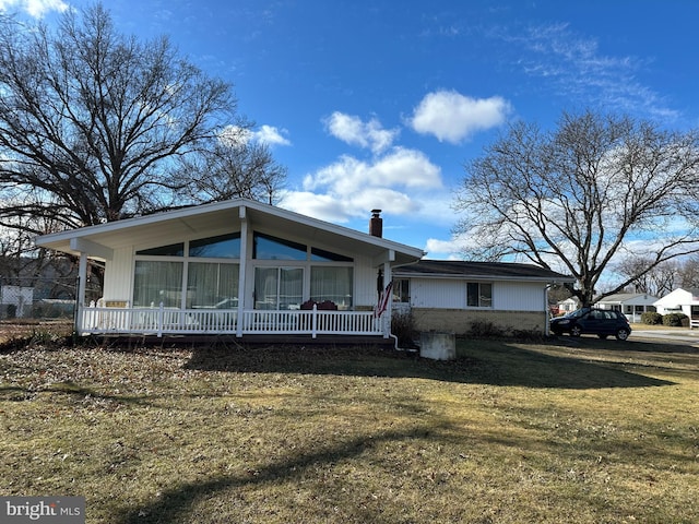 view of front of property with brick siding, a chimney, and a front lawn