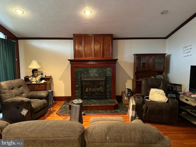 living room with baseboards, a premium fireplace, ornamental molding, wood finished floors, and a textured ceiling