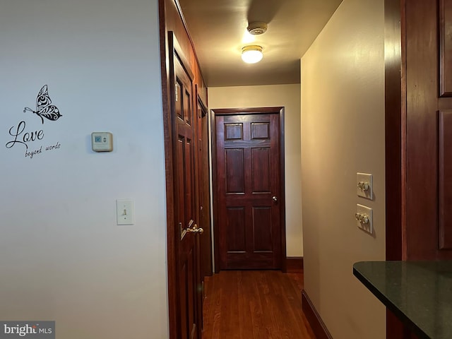 corridor with dark wood-style flooring and baseboards