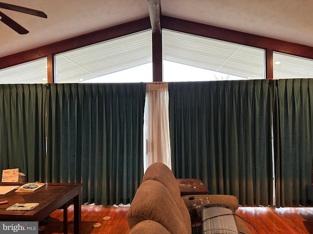 interior space with ceiling fan, beamed ceiling, and wood finished floors