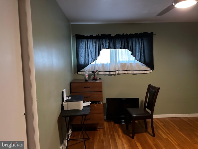 living area with a ceiling fan, baseboards, and wood finished floors