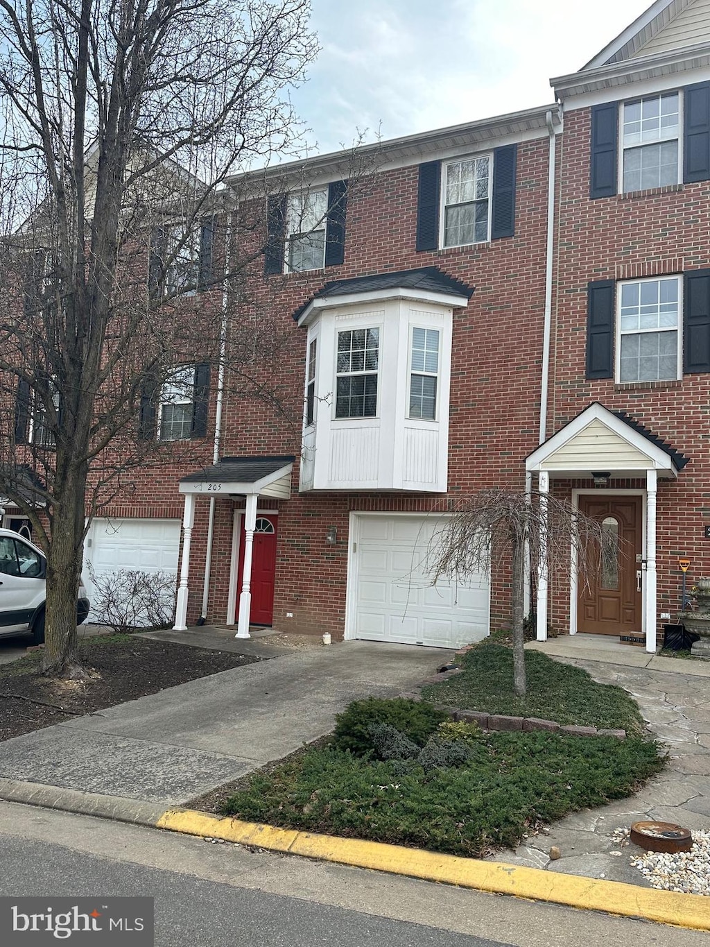 view of property with brick siding, concrete driveway, and an attached garage