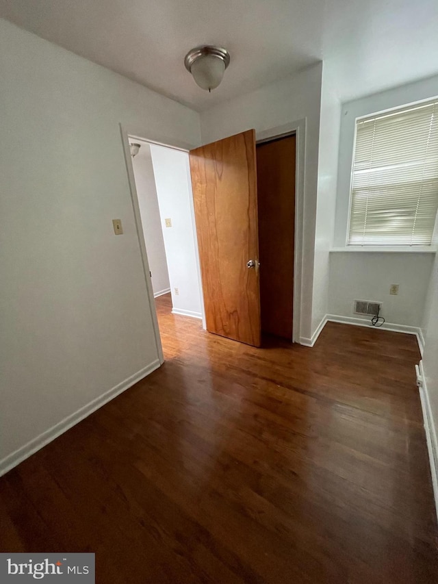 unfurnished room featuring visible vents, baseboards, and wood finished floors