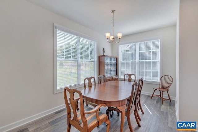 dining area featuring baseboards, a chandelier, and wood finished floors