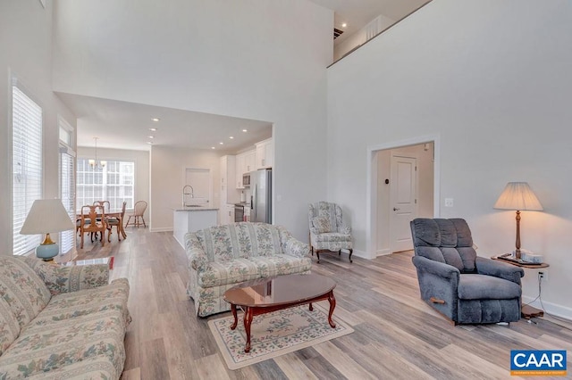 living room with light wood-style floors, a high ceiling, and baseboards