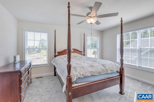 bedroom featuring light carpet, visible vents, baseboards, and multiple windows