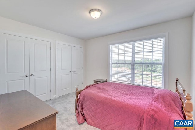 bedroom featuring light carpet and two closets