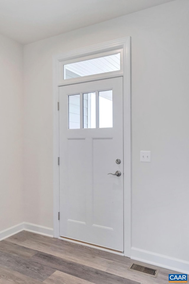 doorway with baseboards, visible vents, and wood finished floors