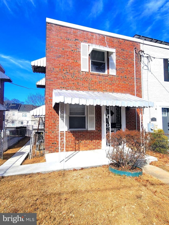 rear view of house with a yard, fence, and brick siding