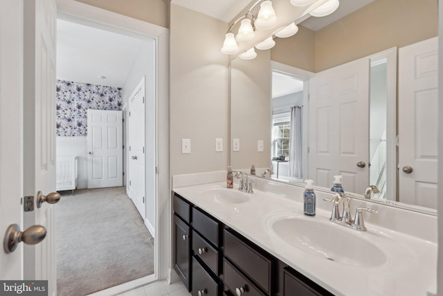 bathroom featuring double vanity, a sink, and wallpapered walls