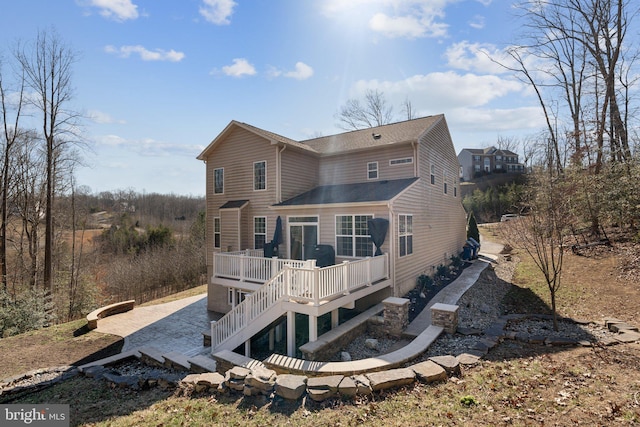 rear view of property featuring a wooden deck, stairs, and a patio