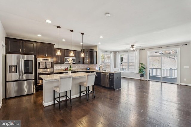 kitchen featuring dark wood-style floors, stainless steel appliances, tasteful backsplash, dark brown cabinetry, and a peninsula