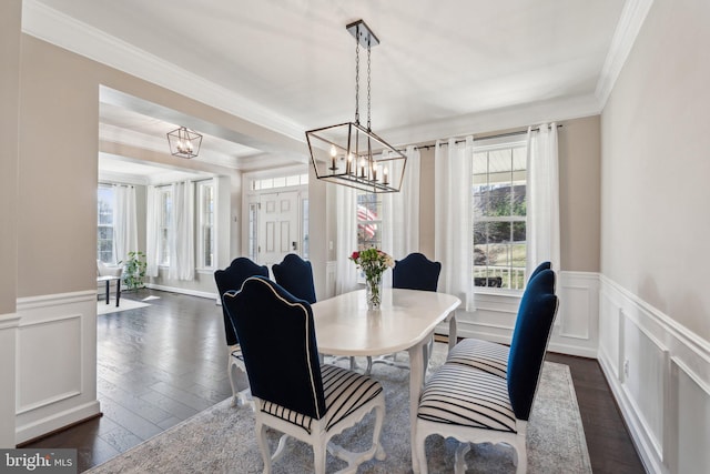 dining space with a chandelier, a decorative wall, and crown molding