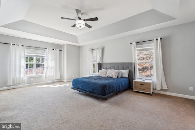 bedroom featuring carpet, baseboards, a raised ceiling, and a ceiling fan