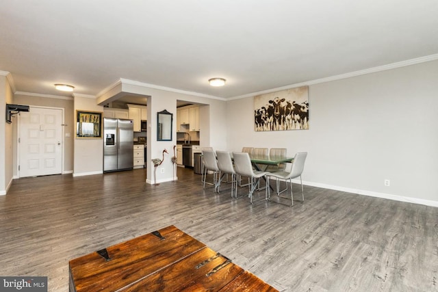 dining room with dark wood-style floors, crown molding, and baseboards