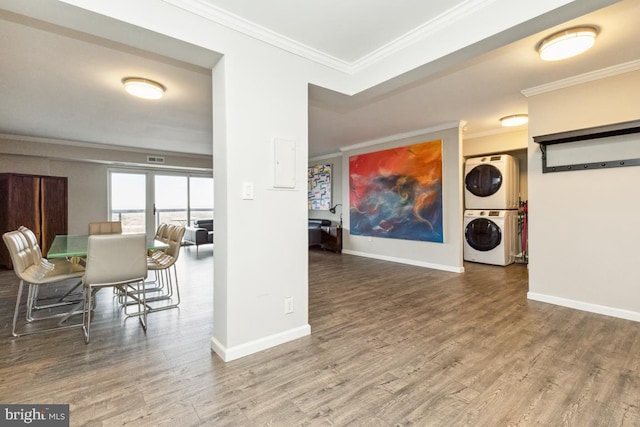 interior space with stacked washer and dryer, baseboards, ornamental molding, and wood finished floors