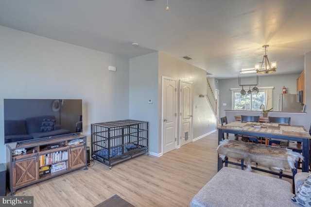 living room with an inviting chandelier, baseboards, visible vents, and wood finished floors