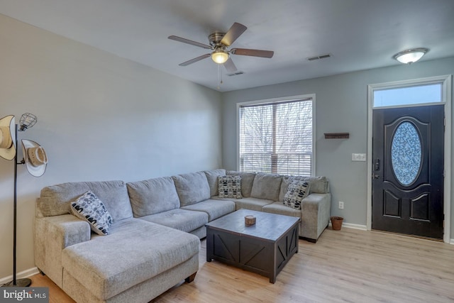 living room featuring light wood-type flooring, baseboards, visible vents, and a ceiling fan