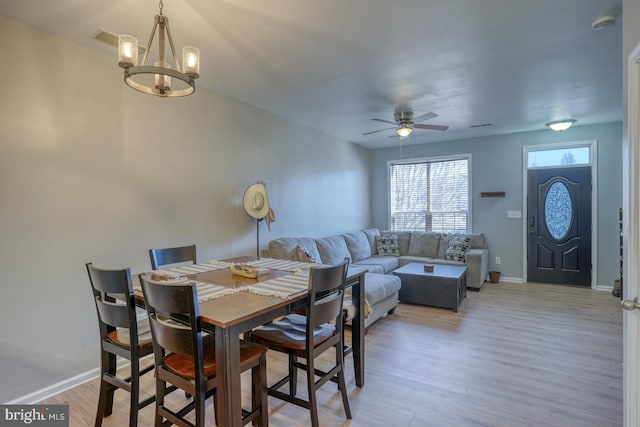 dining room featuring light wood-style flooring, baseboards, and ceiling fan with notable chandelier