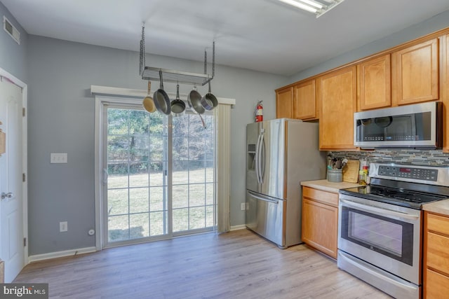 kitchen featuring visible vents, light countertops, appliances with stainless steel finishes, light wood finished floors, and tasteful backsplash