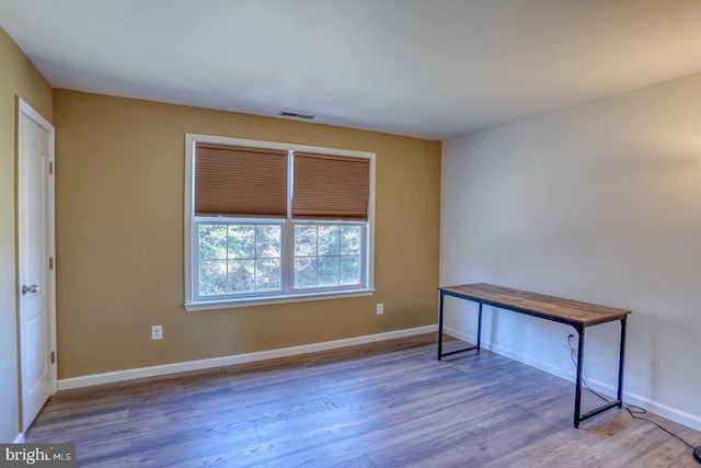 unfurnished office featuring wood finished floors, visible vents, and baseboards