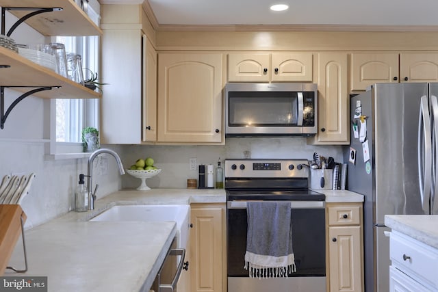 kitchen with stainless steel appliances, a sink, light countertops, ornamental molding, and open shelves