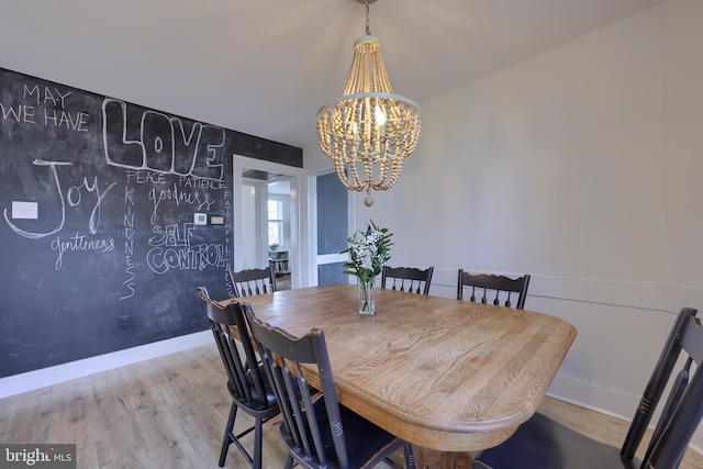 dining room featuring baseboards, wood finished floors, and a notable chandelier