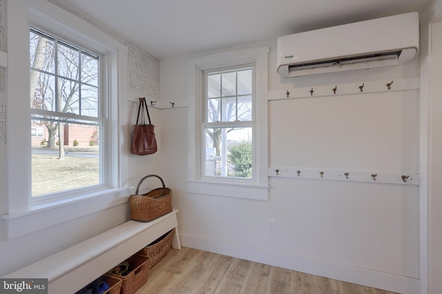 mudroom featuring an AC wall unit, a healthy amount of sunlight, and light wood-style flooring