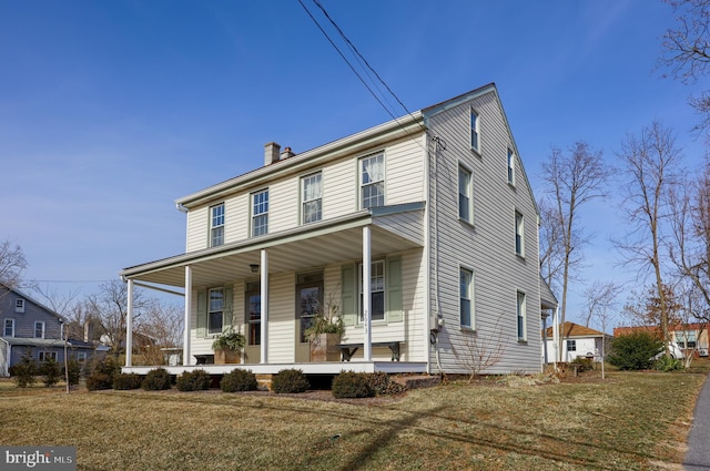 view of front of house with a chimney, a porch, and a front yard