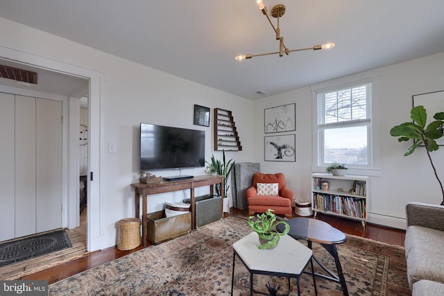 living room with a chandelier, a baseboard radiator, wood-type flooring, and visible vents