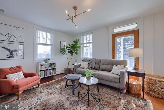 living room with plenty of natural light, visible vents, a chandelier, and wood finished floors