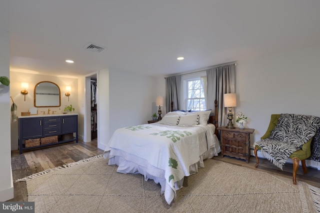 bedroom featuring visible vents, wood finished floors, ensuite bathroom, a spacious closet, and recessed lighting